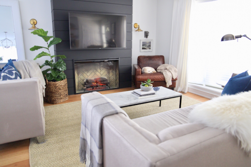 Cozy living room with electric fireplace and TV on a black accent wall.