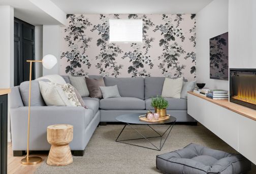 Cozy basement with linear electric fireplace, TV, and accent wall with flowers