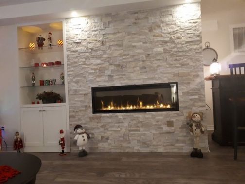 Linear electric fireplace on stone accent wall with Christmas decorations