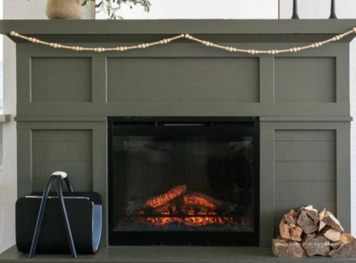 Electric fireplace with dark green mantel decorated for fall.
