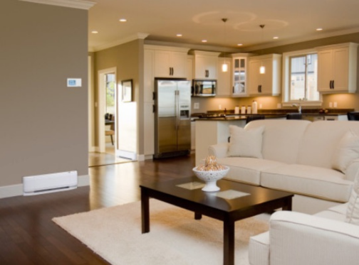 White baseboard heater in modern living room with beige couches, dark brown coffee table and white rug.
