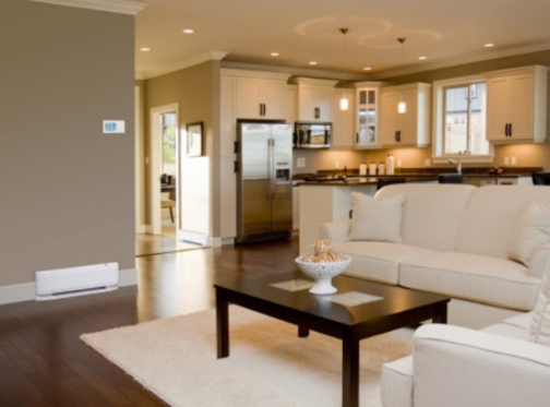 White baseboard heater in modern living room with beige couches, dark brown coffee table and white rug. 