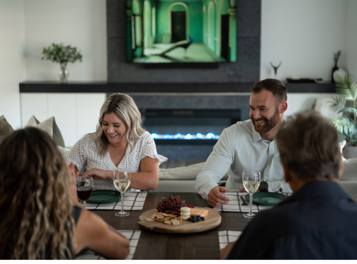 group of people sitting eating at a table by a fireplace