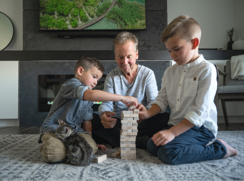 Grandfather and grandchildren playing jenga in front of fireplace