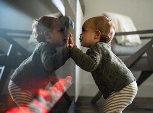 toddler leaning onto fireplace glass