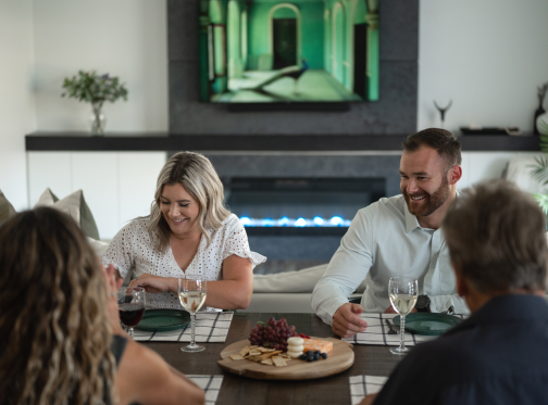 family sitting at table enjoying a meal by a Sierra fireplace