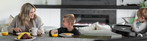 Family eating at a table in the living room by a Sierra fireplace